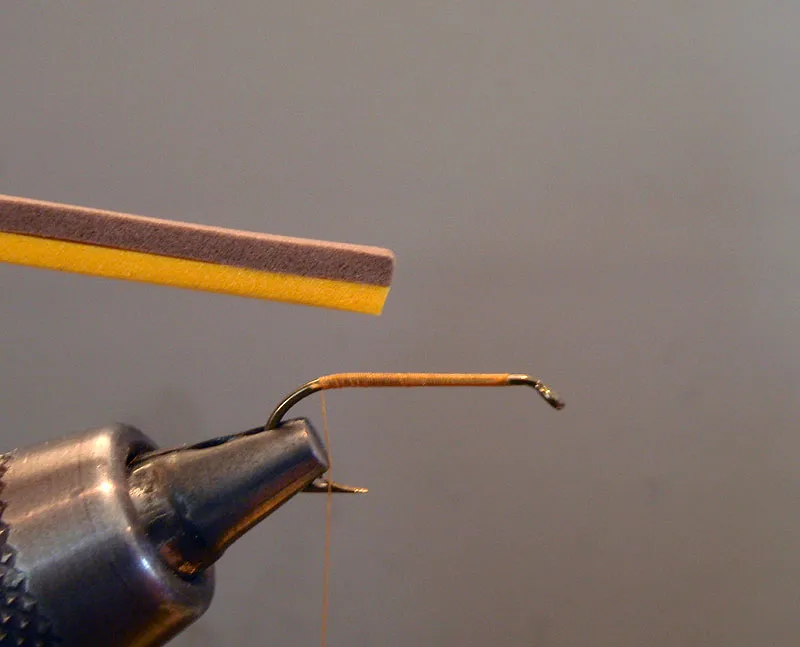 Step 1: Tying in the foam body - Insert hook into vise and start thread, advancing to the rear of the hook shank above the barb. Prepare a small strip of sandwiched bicolor foam about the length of the hook shank and half the width of the hook gap. Here I have chosen a combination of brown and gold to represent a golden stonefly.